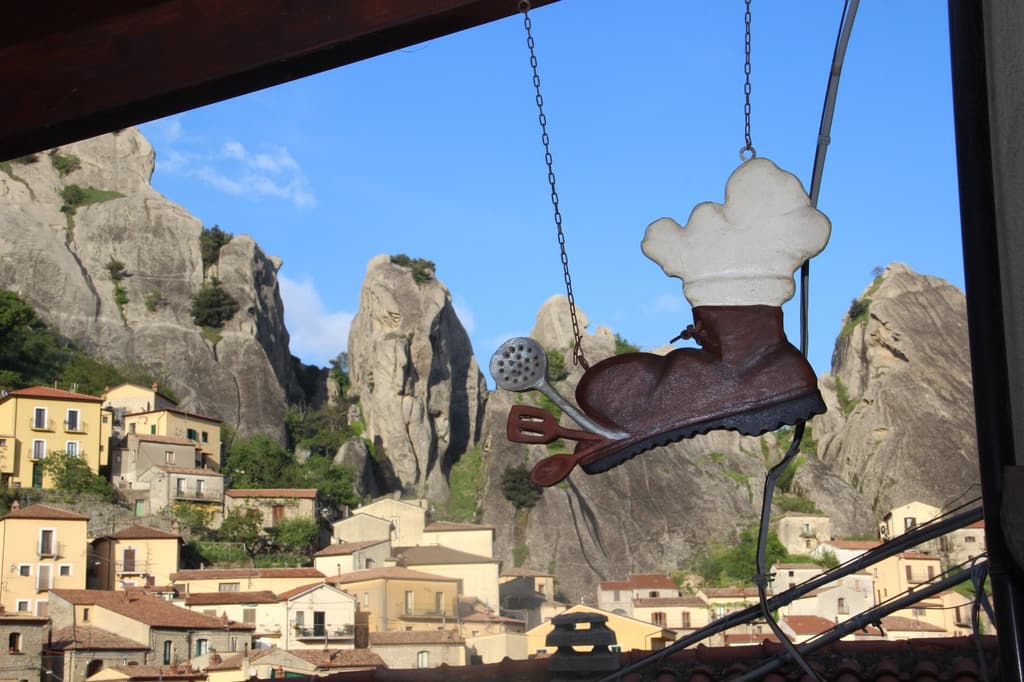 L'insegna in ferro a forma di scarpone con il cappello da cuoco, appesa davanti alle case del paese e alle guglie.